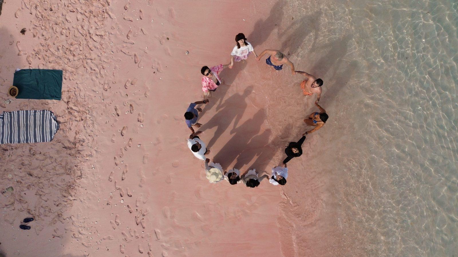 Pink Beach – Aerial group circle on pink sand (Real photo from a KEXI trip)