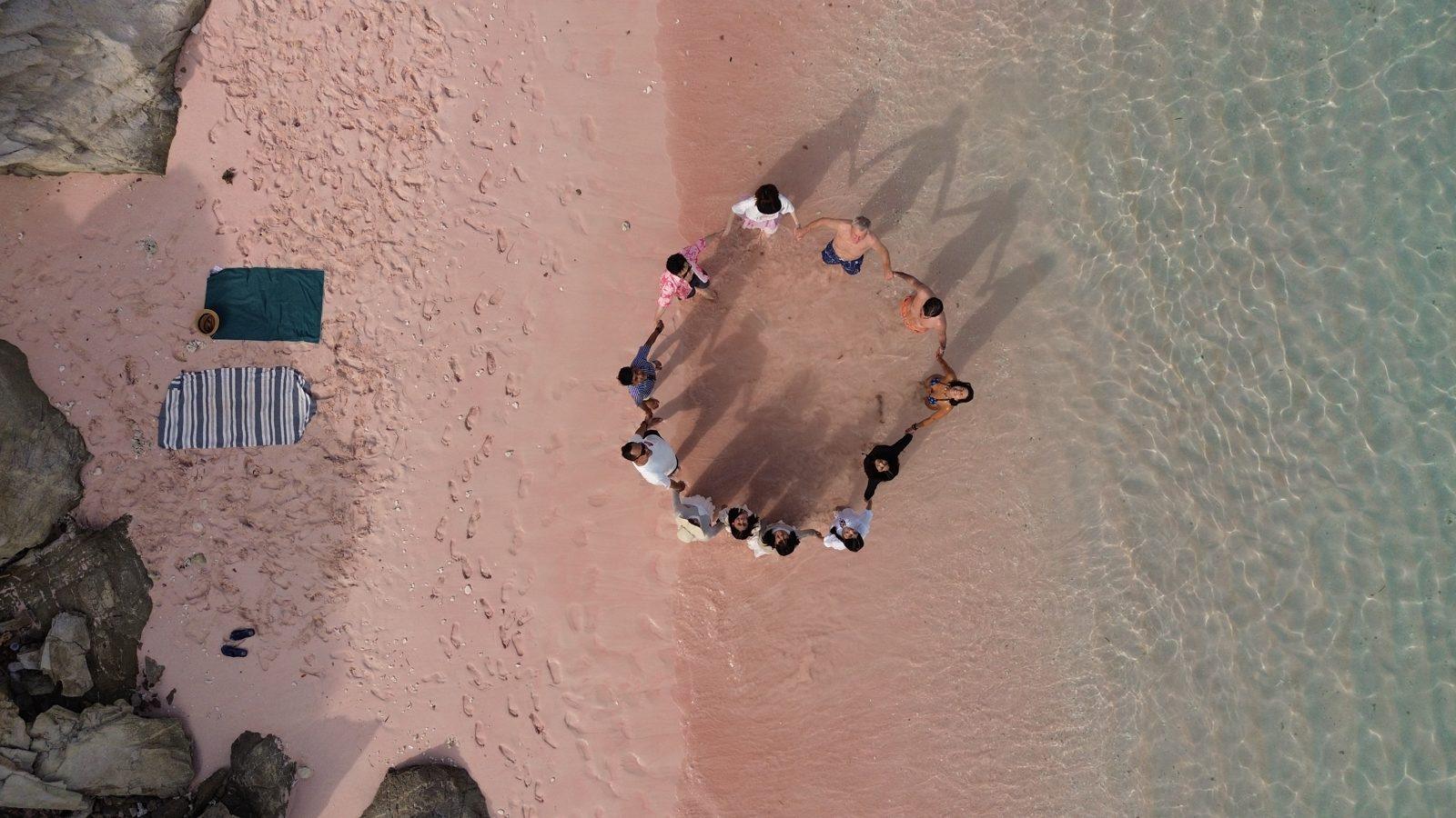 Pink Beach – Aerial group circle, pink sand, turquoise water (Real photo from a KEXI trip)