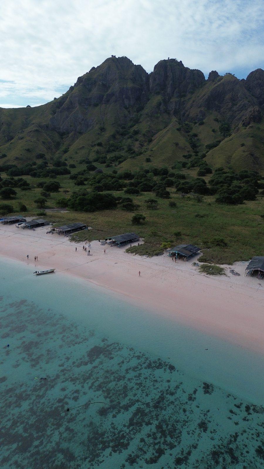 Pink Beach – Aerial pink beach below jagged green ridge (Real photo from a KEXI trip)